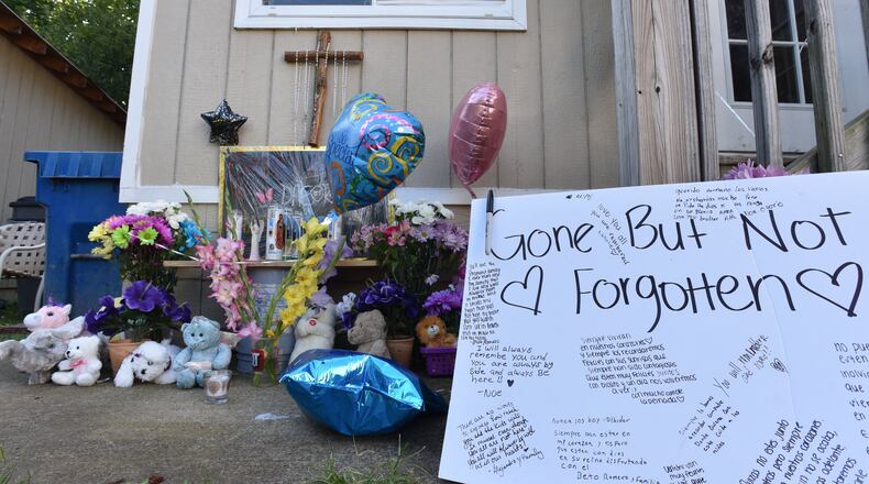 Neighbors and friends placed flowers and messages Thursday night during their gathering on the doorstep of the home where the murders occurred. HYOSUB SHIN / HSHIN@AJC.COM