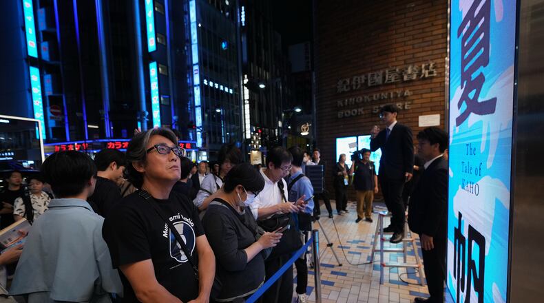 People attend a countdown event to receive copies they pre-purchased, of Haruki Murakami's new book, titled "The Tale of KAHO" after the clock strikes midnight, at a Kinokuniya bookstore in Tokyo on Thursday, July 2, 2026. (AP Photo/Hiro Komae)