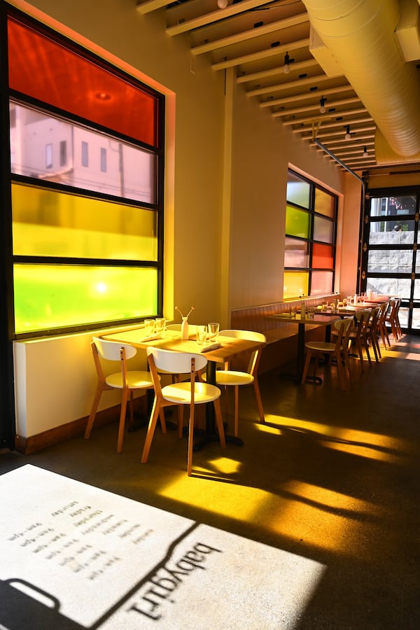 A restaurant dining room with many windows covered in multicolored film.