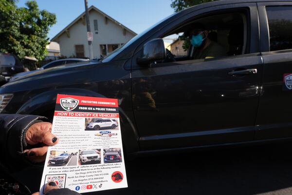 A member of the Union del Barrio, a grassroots political organization, distributes a "How to Identify ICE vehicles" flyer to people living in Los Angeles, Monday, June 16, 2025. (AP Photo/Damian Dovarganes)