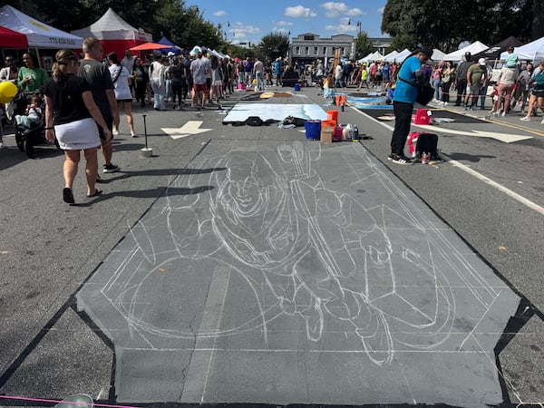 Artists from around the globe are doing work at Chalktoberfest in Marietta. Pictured is an outline of chalk art being worked on Saturday, Oct. 11, 2025, by Ruven Poncia, who is based in Utrecht, Netherlands. (Caleb Groves/AJC)
