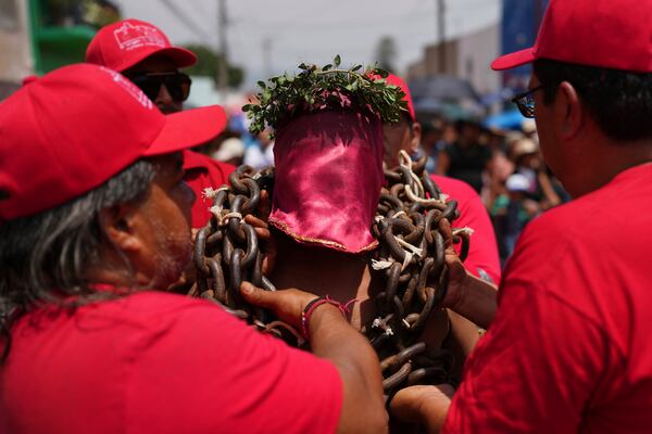 A masked penitent is helped with the chains he bears during a Holy Week procession in Atlixco, Mexico, on Good Friday, April 18, 2025. (AP Photo/Eduardo Verdugo)