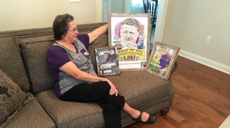 In this Aug. 22, 2017 photo, Cornelia "Coco" Orgeron, shows off memorabilia marking the ascension of her son, Ed Orgeron, to head coach at LSU, at her home in Larose, La. Ed Orgeron grew up an LSU fan in Cajun country along the Bayou Lafourche in Larose, Louisiana, where his mother still lives. The Tigers' coach is about to begin his first full season on the job after taking over for Les Miles during last season. His Louisiana and Cajun roots made him a popular choice to keep the job long term. (AP Photo/Brett Martel)