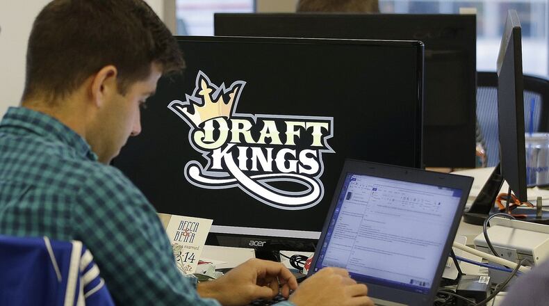 FILE - In this Sept. 9, 2015, file photo, Bear Duker, a marketing manager for strategic partnerships at DraftKings, works at his computer at the company headquarters in Boston. Daily fantasy sports rivals DraftKings and FanDuel have agreed to merge after months of speculation and increasing regulatory scrutiny. The two companies made the announcement Friday, Nov. 18, 2016, saying the combined organization would be able to reduce costs as they work to become profitable and battle with regulators across the country to remain legal. (AP Photo/Stephan Savoia, File)