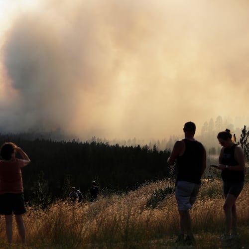 People watch Old Trails Fire from W. Northwest Blvd., Saturday, Aug. 1, 2026, in Spokane, Wash. (AP Photo/Young Kwak)