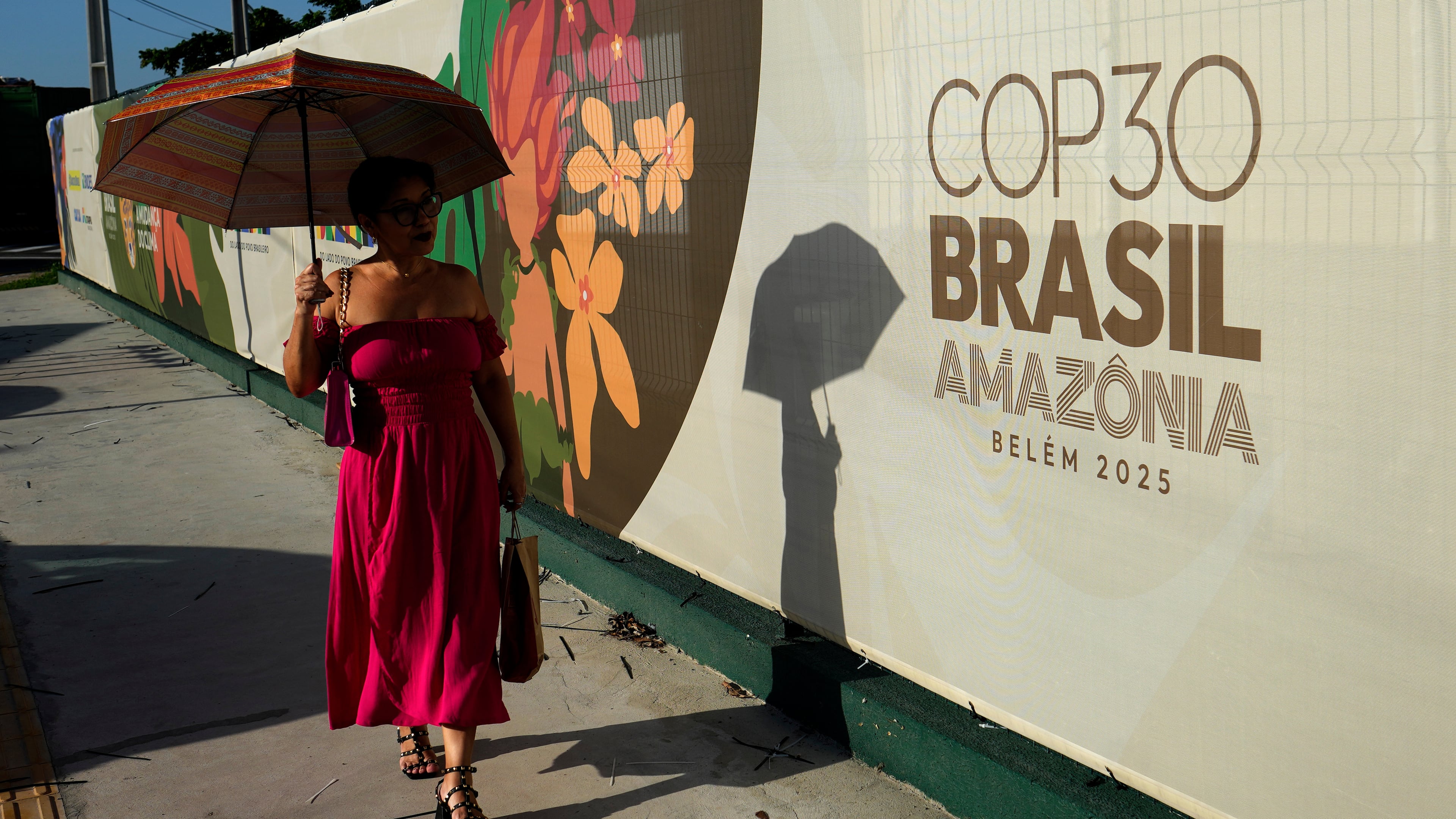 A woman walks past a sign for the COP30 U.N. Climate Summit, in Belem, Para state, Brazil, Tuesday, November 4, 2025. (AP Photo/Eraldo Peres)