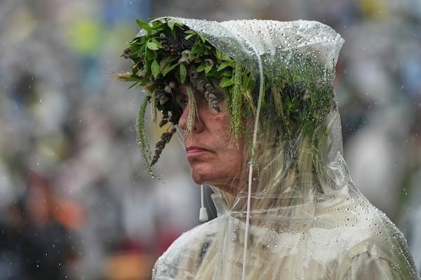 A spectator braves the rain as she watches the song festival, part of the "Iseoma" Song and Dance Celebration, at the Song Festival Grounds in Tallinn, Estonia, Sunday, July 6, 2025. (AP Photo/Sergei Grits)