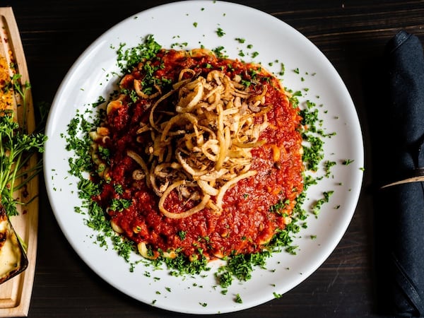A topping of crisp fried onions and a tangy garlic dressing provide both crunch and punch to the koshari at Pharaohs Palace. (Henri Hollis/AJC)