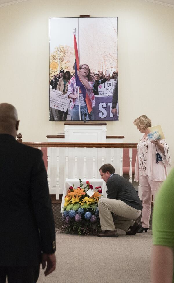 Flowers are gathered up below a photo of Scout Schultz, the Georgia Tech student shot and killed by a campus police officer in September. At the memorial service, Schultz was remembered as a brilliant student, passionate activist and someone whose death should be a clarion call for better understanding of mental health. (JOHN AMIS / SPECIAL TO THE AJC)