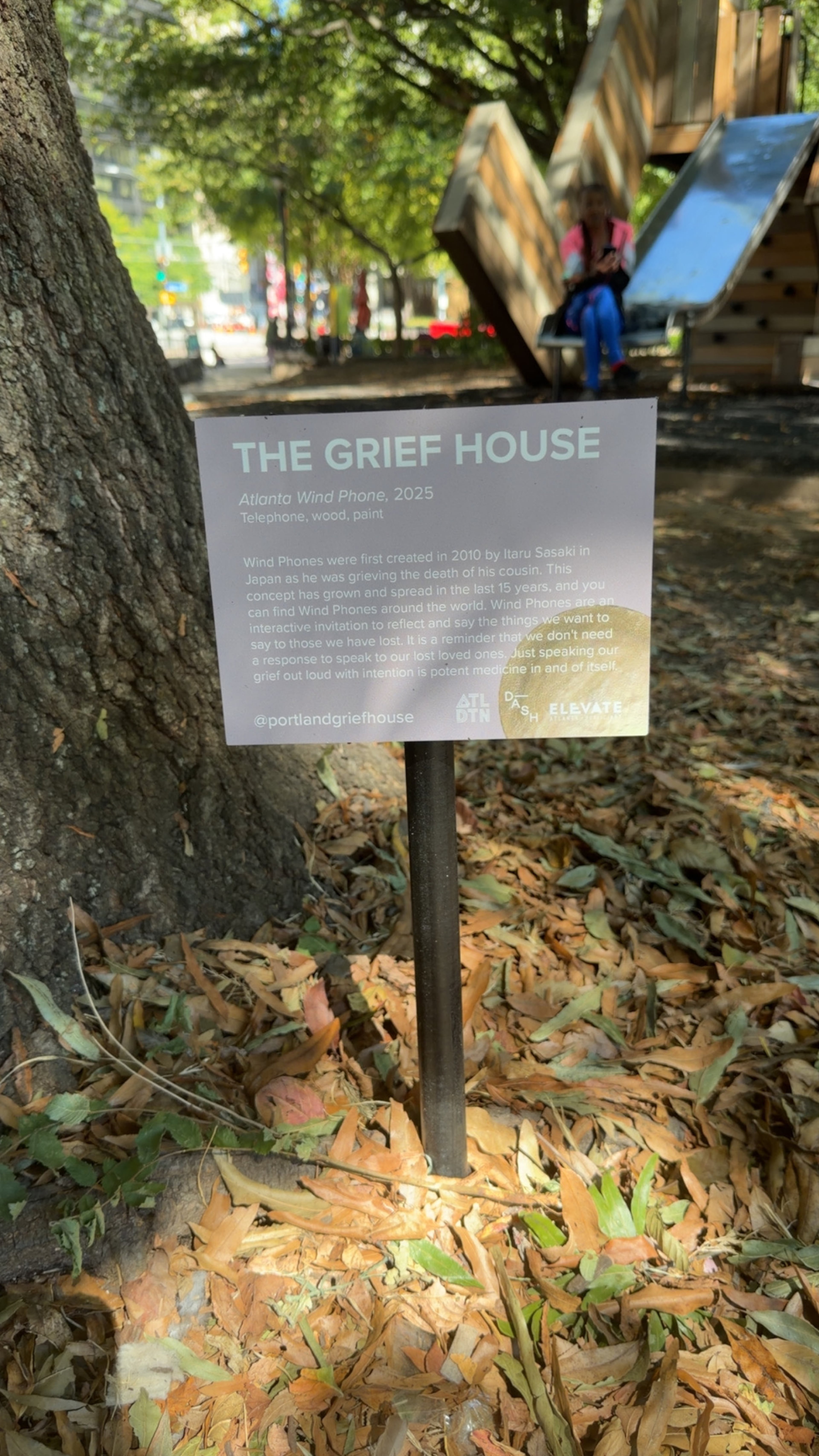 Featured as part of an art installation in Woodruff Park, a sign from Atlanta nonprofit the Grief House details the origin of wind phones. (Courtesy of Pamela Elder)