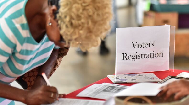 Sharon Huff of Atlanta fills in a voter registration form at a desk that the group Asian Americans Advancing Justice-Atlanta set up in The Sweet Auburn Curb Market in August. HYOSUB SHIN / HSHIN@AJC.COM