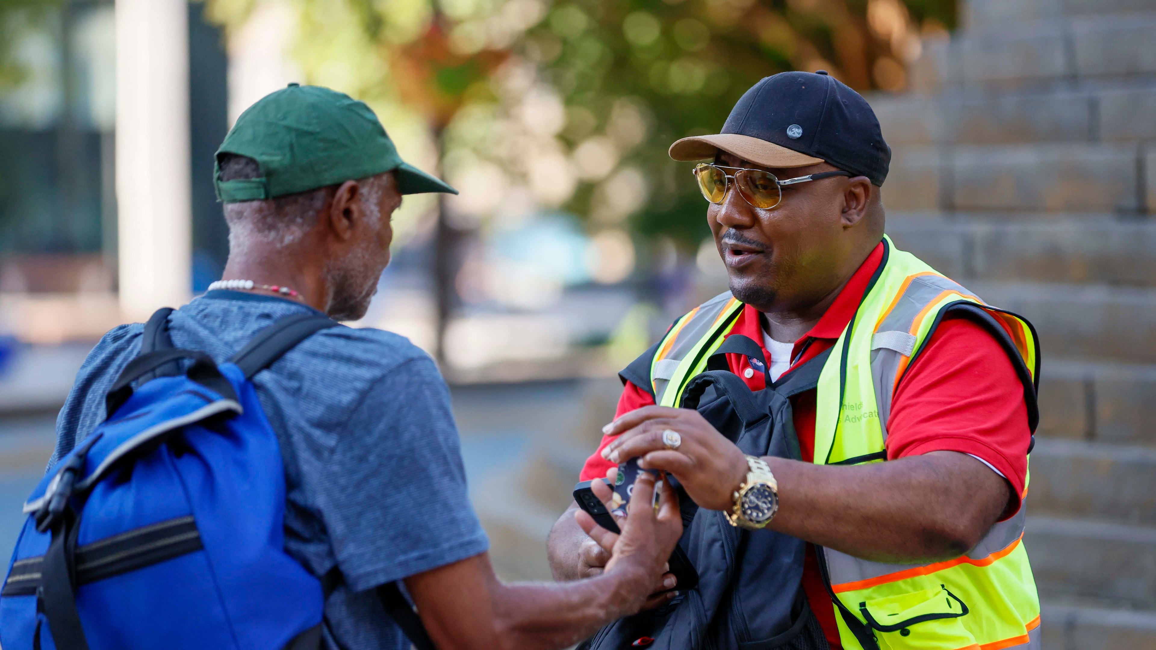 Richard DeShields, with Partner for HOME, right, speaks while conducting a survey of homeless individuals at Wudruff Park on Monday, July 7, 2025. This survey helps inform the Downtown Rising strategy to house people and prevent them from sleeping outside before and after the World Cup. (Miguel Martinez/AJC)
