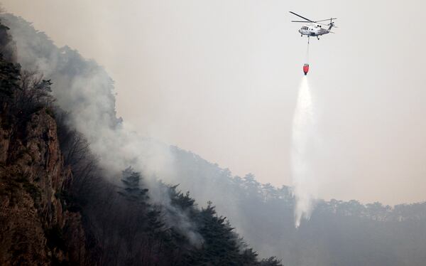 A helicopter tries to extinguish a wildfire by dropping water at a national park in Cheongsong, South Korea, Thursday, March 27, 2025. (Lee Moo-yeol/Newsis via AP)