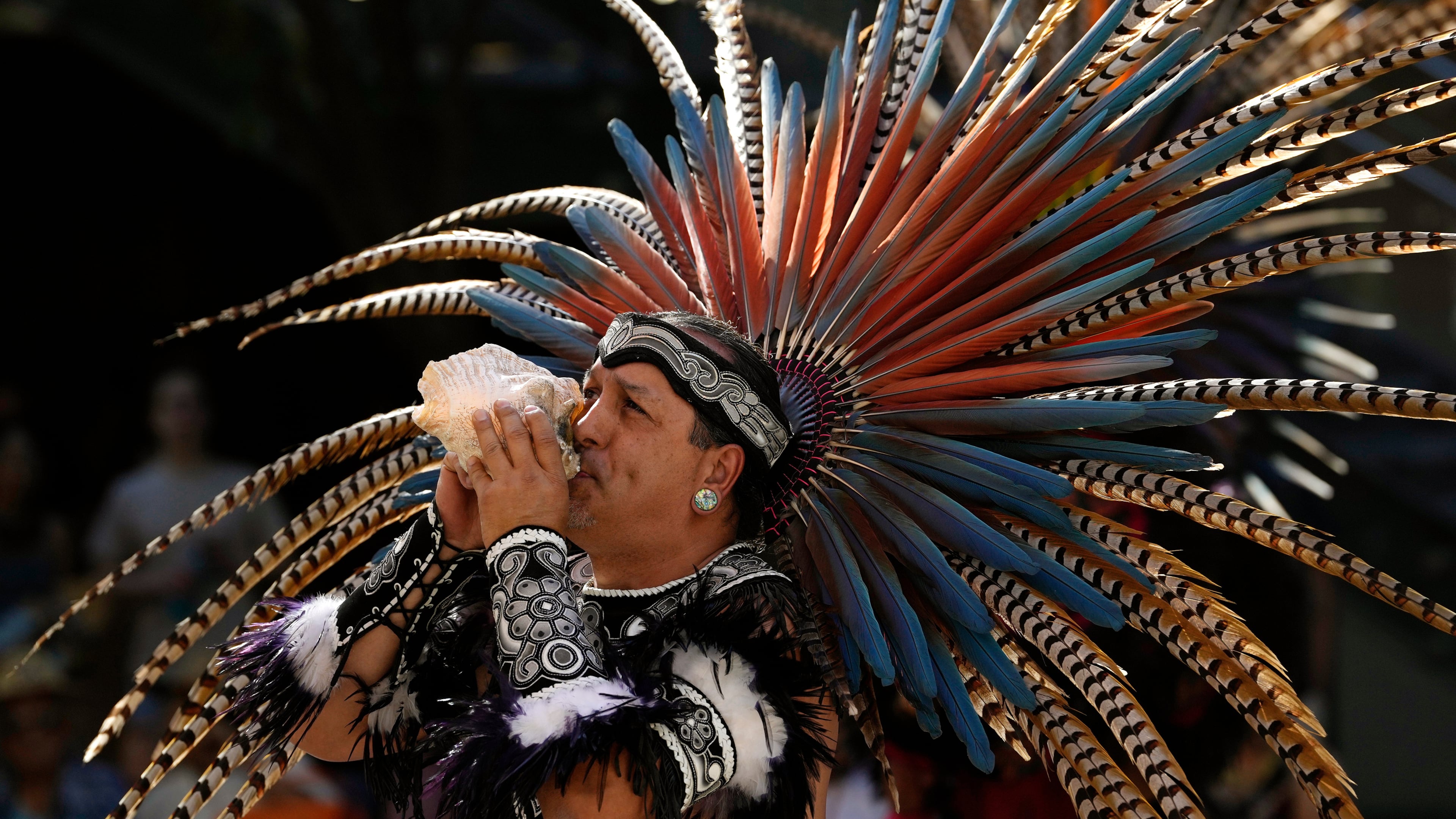 FILE - A member of the Grupo Coatlicue blows on a conch shell during a performance of a traditional Aztec dance, an agricultural prayer ceremony in motion, during an Indigenous Peoples' Day event, Oct. 14, 2024, in Phoenix. (AP Photo/Ross D. Franklin, File)