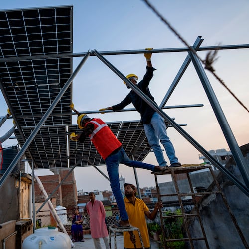 FILE - Workers install solar panels on a rooftop of a home in Prayagraj, India, Monday, Oct. 14, 2024. (AP Photo/Rajesh Kumar Singh, File)