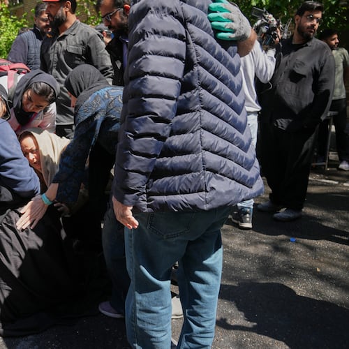 Bystanders try to comfort and assist a woman as she reacts near the site of a strike that, according to a security official at the scene, destroyed half of the Khorasaniha Synagogue and nearby residential buildings in Tehran, Iran, Tuesday, April 7, 2026. (AP Photo/Francisco Seco)