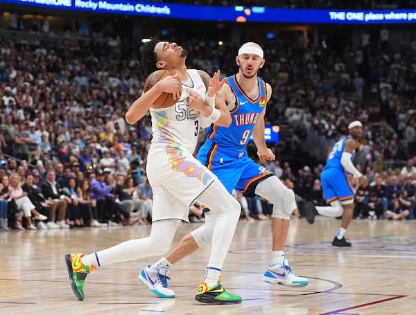 Denver Nuggets guard Julian Strawther, front, is fouled by Oklahoma City Thunder guard Alex Caruso in the second half of Game 6 in the Western Conference semifinals of the NBA basketball playoffs Thursday, May 15, 2025, in Denver. (AP Photo/David Zalubowski)