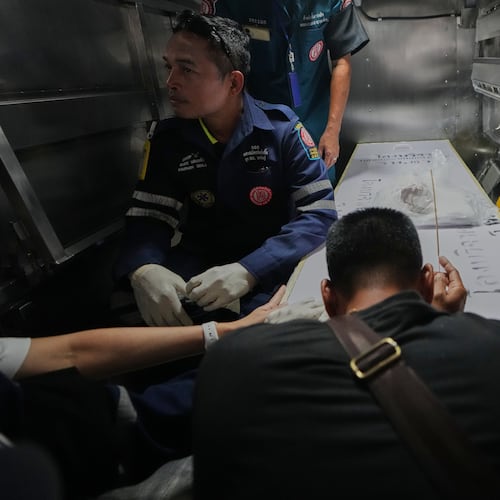 A relative of a victim in a music bar fire pays respect to the victim's body at a police hospital in Bangkok, Thailand, Tuesday, July 14, 2026. (AP Photo/Sakchai Lalit)