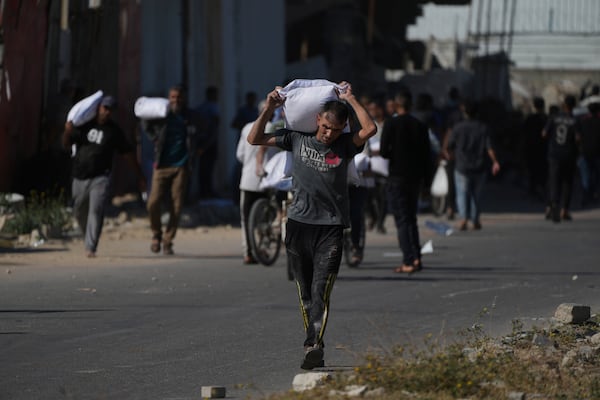 Palestinians carry bags of flour after storming a U.N. World Food Program warehouse in Zawaida, Central Gaza Strip, on Wednesday, May 28, 2025. (AP Photo/Abdel Kareem Hana)