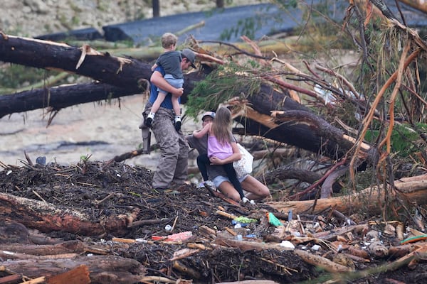 A woman falls while climbing with others over debris on a bridge atop the Guadalupe River after a flash flood swept through the area Saturday, July 5, 2025, in Ingram, Texas. (AP Photo/Julio Cortez)