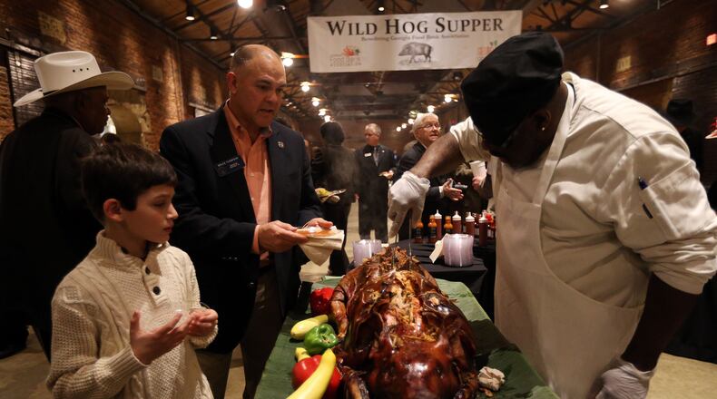Chef Michel Penton serves up pork to state Sen. Bruce Thompson, R-White, and his son Max during the 53rd annual Wild Hog Supper in January 2015. The supper, the traditional kickoff to the legislative session, has been rescheduled for Feb. 27 after the threat of bad weather canceled it earlier this month. BEN GRAY / BGRAY@AJC.COM