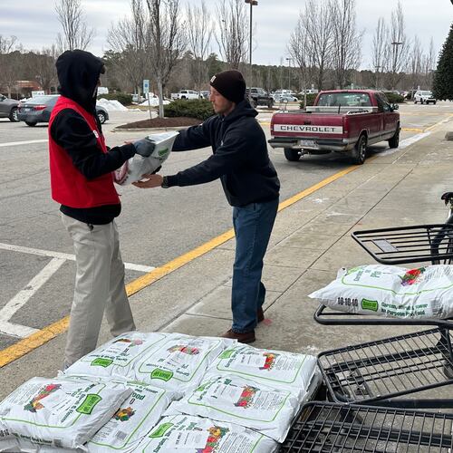 Hunter Steffen, 17, left, hands a hard-to-come by 40-pound bag of ice melt to a customer outside Town & County Hardware in Wake Forest, N.C., on Saturday, Jan. 31, 2026. (AP Photo/Allen G. Breed)