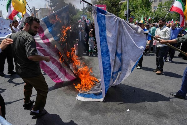 Iranian protestors burn representations of the Israeli and U.S. flags during a protest to condemn Israeli attacks on multiple cities across Iran, after the Friday prayers ceremony in Tehran, Iran, Friday, June 20, 2025. (AP Photo/Vahid Salemi)