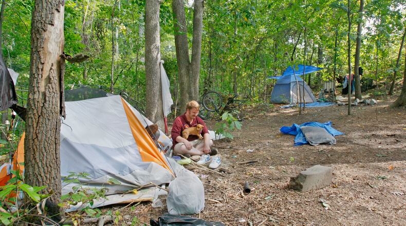 In this 2009 AJC file photo, Mark Miechurski, 30, sits outside his tent with dog "Trista", and girlfriend, Cindy Baker, 37, inside the tent, who is on disability and trying to help him get a place to live. A small group of homeless sex offenders have set up camp in a densely wooded area behind a Cobb County office park, directed there by probation officers who say it's a place of last resort for those with nowhere else to go. Bob Andres, bandres@ajc.com