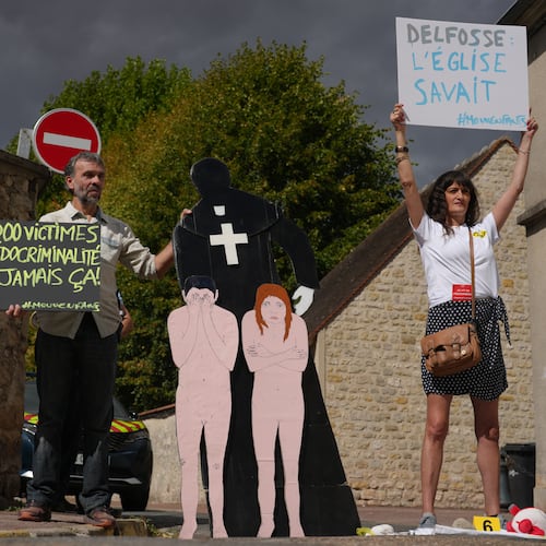 Activists fighting child abuse stage a protest near the home of a former Catholic priest suspected of sexually assaulting dozens of children, in Etrechy, outside Paris, Wednesday, Sept 16, 2026, Placards read from the left: '330,000 victims of child sexual abuse, never again' and Delfosse, the church knew'. (AP Photo/Thibault Camus)