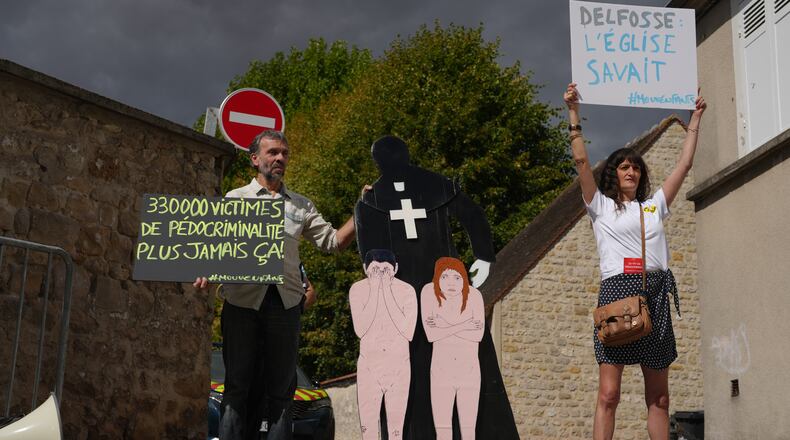 Activists fighting child abuse stage a protest near the home of a former Catholic priest suspected of sexually assaulting dozens of children, in Etrechy, outside Paris, Wednesday, Sept 16, 2026, Placards read from the left: '330,000 victims of child sexual abuse, never again' and Delfosse, the church knew'. (AP Photo/Thibault Camus)