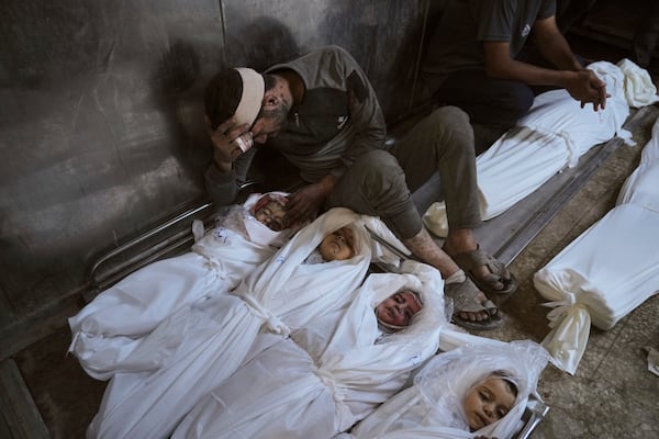 EDS NOTE: GRAPHIC CONTENT - Hossam Azzam mourns over the body of his son, Amir, and other relatives who were killed in an Israeli military airstrike on Gaza, at Shifa Hospital in Gaza City Tuesday, July 15, 2025. (AP Photo/Jehad Alshrafi)