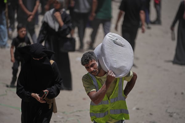 Palestinians carry bags of flour distributed by the World Food Programme (WFP) in Gaza City, northern Gaza Strip, Saturday, July 12, 2025. (AP Photo/Jehad Alshrafi)