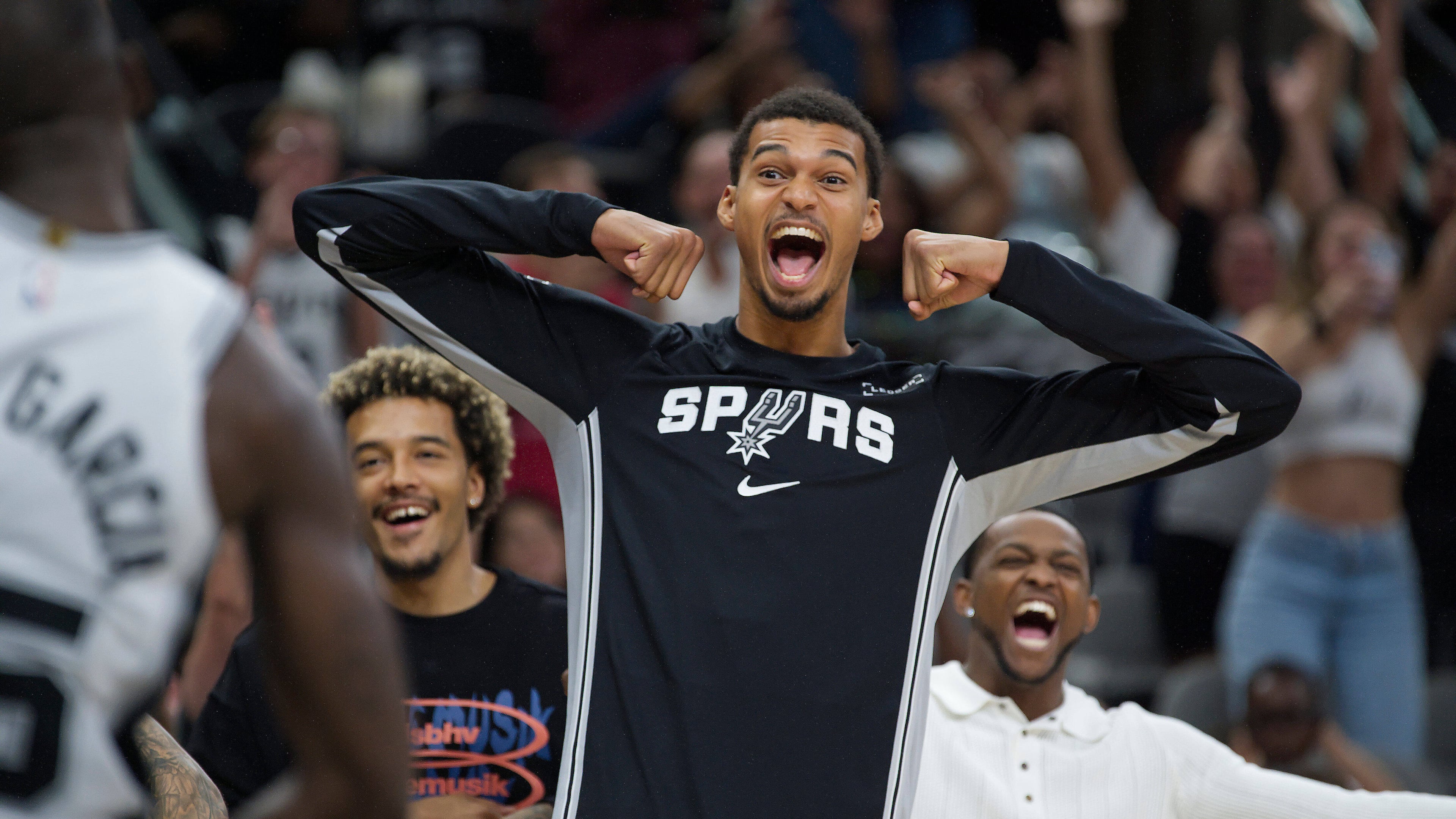 San Antonio Spurs center Victor Wembanyama, center, celebrates after a basket by Spurs guard David Jones Garcia, left, in overtime during a preseason NBA basketball game against the Utah Jazz, Friday, Oct. 10, 2025, in San Antonio. (AP Photo/Darren Abate)