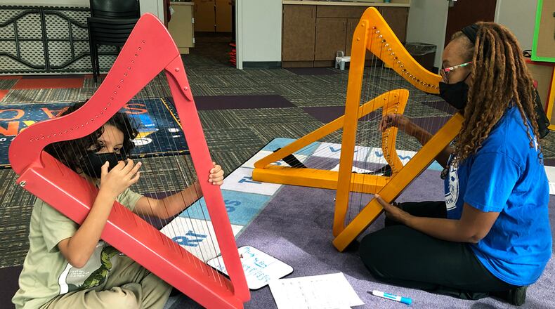 Lyrika Holmes (left) of Artz for the Harp leads Ezra Durden through his first lesson at the South Cobb Regional Library.