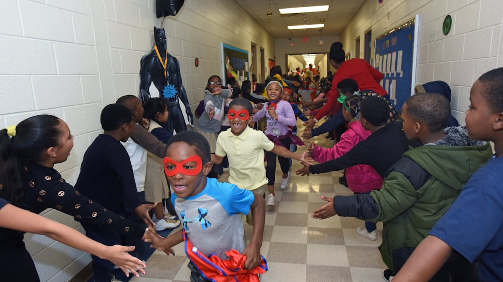 Students participate in the Friday attendance run at Miles Elementary School on Friday, Nov. 22, 2019. Students with good attendance get to run around the hallways dressed up in capes and masks as superheroes. (AJC FILE).