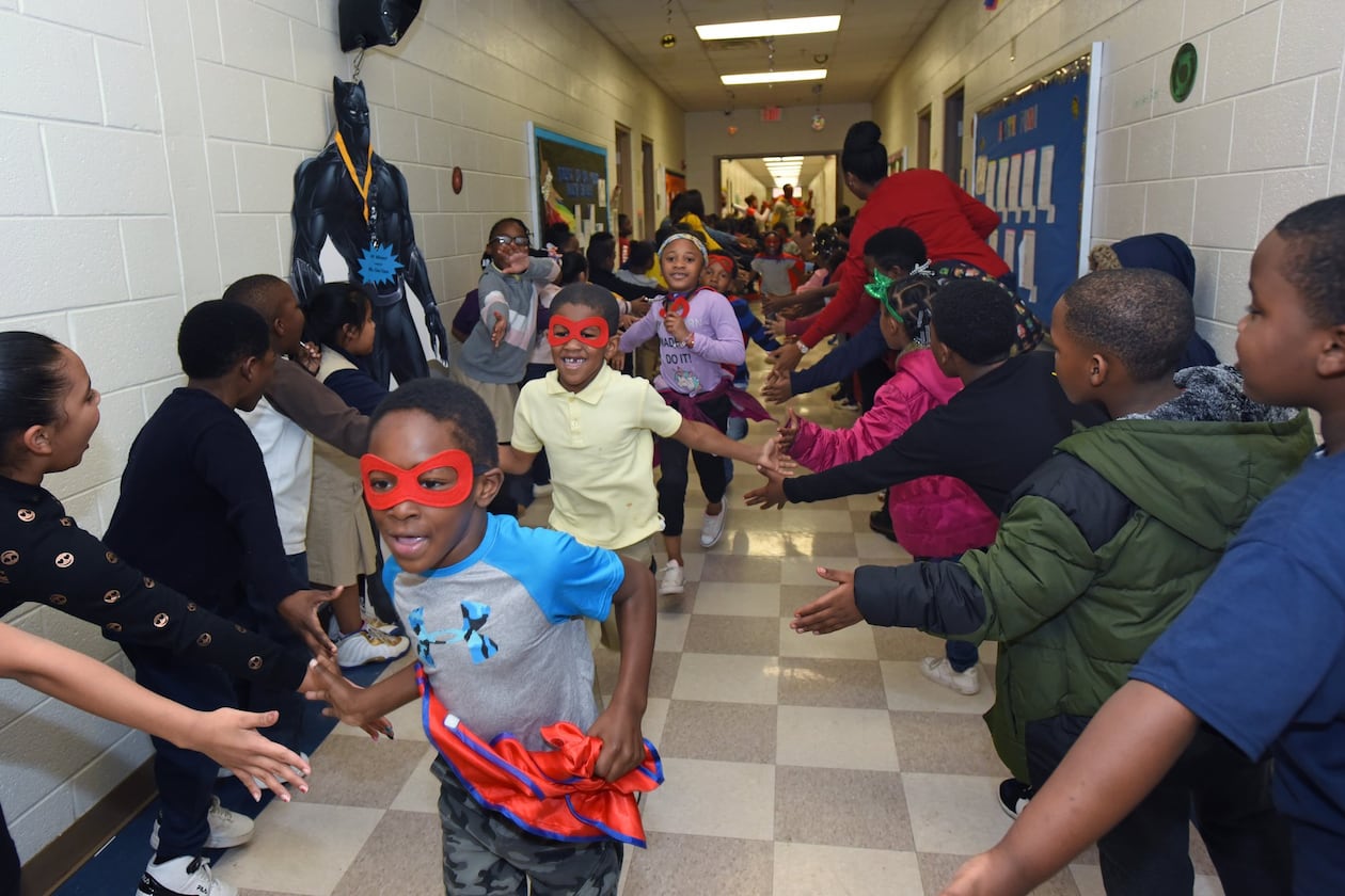 Students participate in the Friday attendance run at Miles Elementary School on Friday, Nov. 22, 2019. Students with good attendance get to run around the hallways dressed up in capes and masks as superheroes. (AJC FILE).