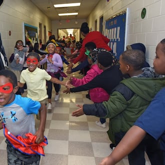 Students participate in the Friday attendance run at Miles Elementary School on Friday, Nov. 22, 2019. Students with good attendance get to run around the hallways dressed up in capes and masks as superheroes. (AJC FILE).