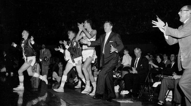 Coach Frank McGuire, center, and players of North Carolina University jump from the bench and cheer as their team defeats Michigan State 74-70 in the third overtime period in the semi-final game of the NCAA championship tournament in Kansas City, Mo., on March 22, 1957. (AP Photo)