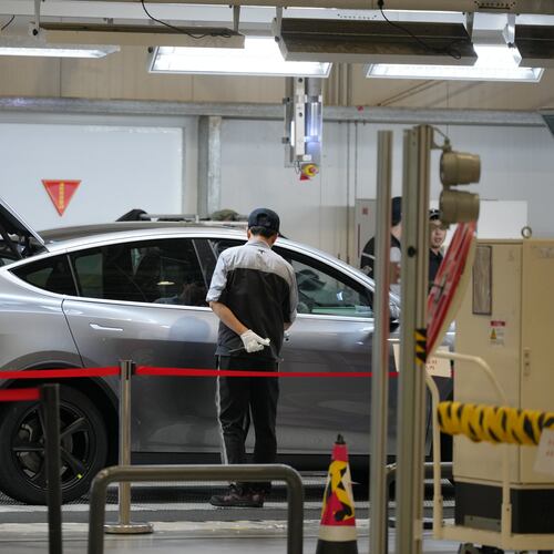 Workers check on the Tesla Model Y at the production lines at the Tesla Gigafactory assembly plant during a media organized tour, in Shanghai, China, Tuesday, April 14, 2026. (AP Photo/Andy Wong)