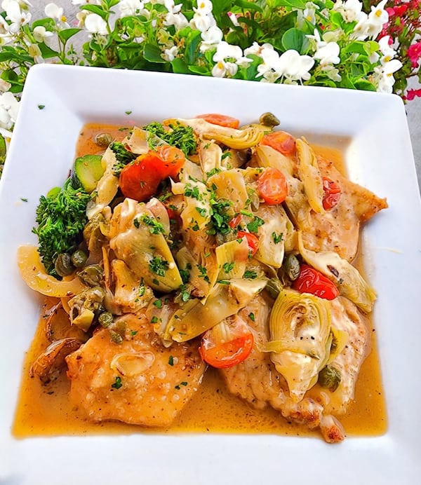A square plate of chicken piccata.