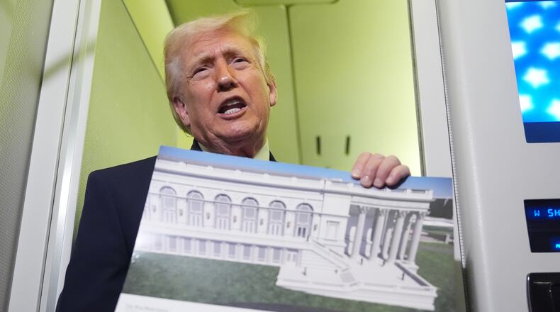 President Donald Trump holds a rendering of the proposed new East Wing of the White House as he speaks to reporters aboard Air Force One en route from West Palm Beach, Fla., to Joint Base Andrews, Md., Sunday, March 29, 2026. (AP Photo/Mark Schiefelbein)