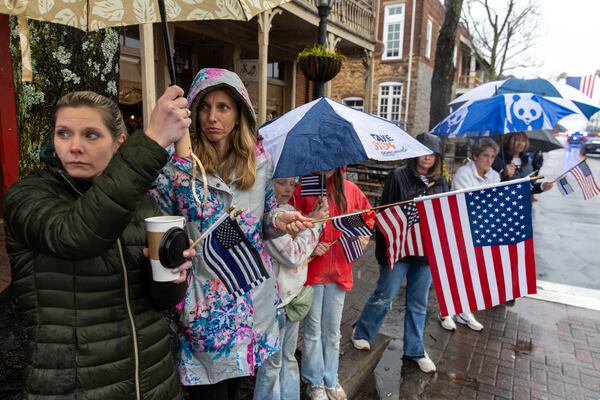 Mourners watch as a funeral procession for fallen police officer Jeremy Labonte drives through downtown Roswell on Wednesday, February 12, 2025. The 24-year-old Roswell Police Department officer was shot to death on Friday evening. (Arvin Temkar / AJC)