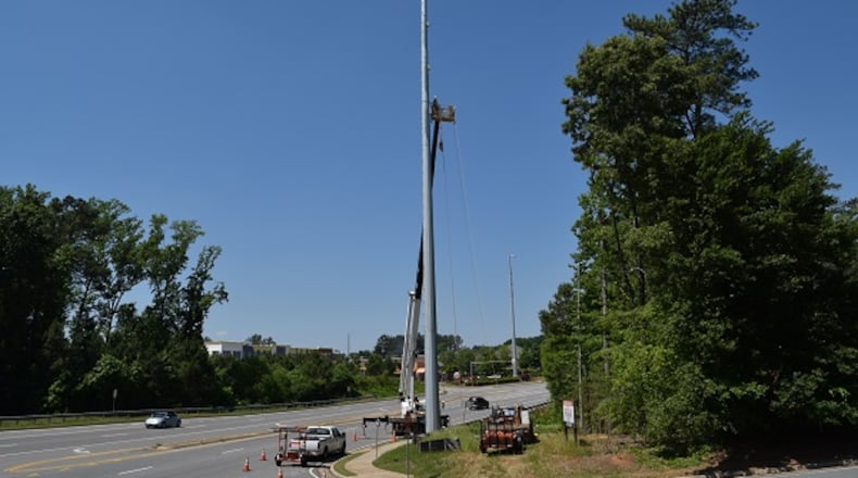 A lineman works on a newly installed 120 foot tall electric transmission tower along Ronald Reagan Boulevard near Cumming. it is one of 79 new towers put in place to provide for current and projected future energy needs in Forsyth County. Marty Farrell for the AJC