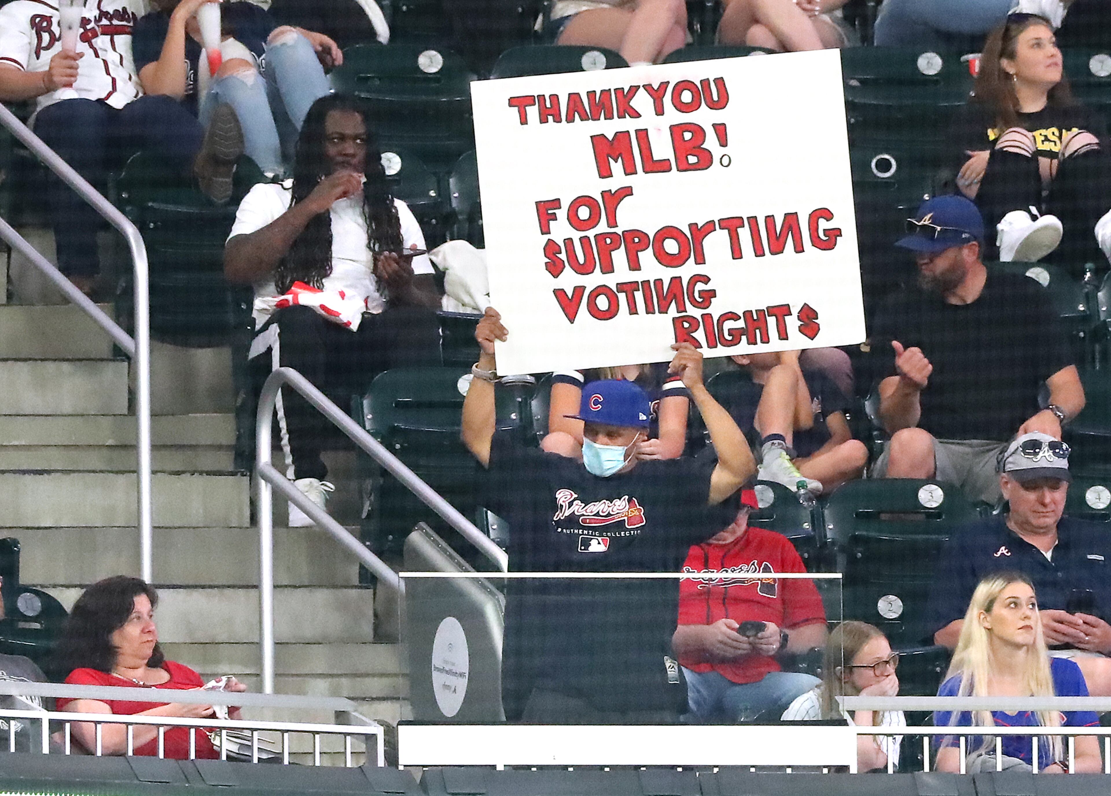 A fan holds a sign thanking Major League Baseball for "supporting voting rights" during a game at Truist Park in Atlanta in 2021.