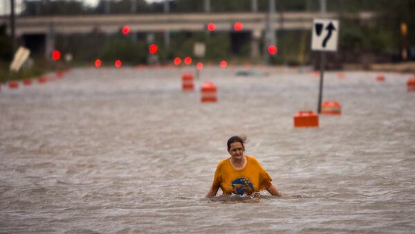 A woman who identified herself as Valerie walks along flooded President Street after leaving her homeless camp after Hurricane Matthew caused flooding, Saturday, Oct. 8, 2016, in Savannah, Ga. Matthew plowed north along the Atlantic coast, flooding towns and gouging out roads in its path. (AP Photo/Stephen B. Morton)