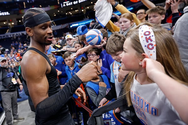 Oklahoma City Thunder guard Shai Gilgeous-Alexander, left, talks to a fan as he signs autographs before an NBA basketball game against the Los Angeles Lakers, Sunday, April 6, 2025, in Oklahoma City. (AP Photo/Nate Billings)