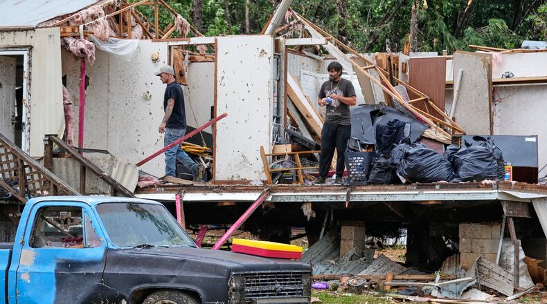 People stand among debris at Gene's Mobile Home Supply, a trailer park in Bogue Chitto, Miss., Thursday, May, 7, 2026, after a tornado cut across the state. (AP Photo/Gerald Herbert)