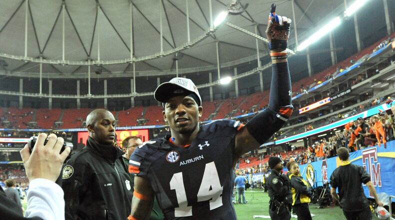 Auburn quarterback Nick Marshall (14) leaves the field as fans celebrate a 59-42 victory against Missouri in the SEC Championship game at the Georgia Dome in Atlanta, Saturday, Dec. 7, 2013.