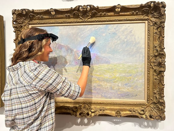 Megan Shores, a collection care technician, gently dusts a painting. Photo: Courtesy of High Museum of Art