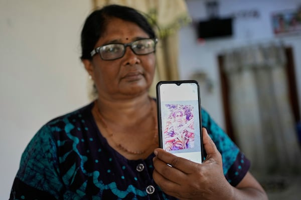 Thavarathnam Pushparani holds up her mobile phone to show a portrait of herself from the time she fought for the now-defeated Tamil Tiger rebels against Sri Lankan forces, at her home in Paranthan, Sri Lanka, Thursday, March 27, 2025. (AP Photo/Eranga Jayawardena)